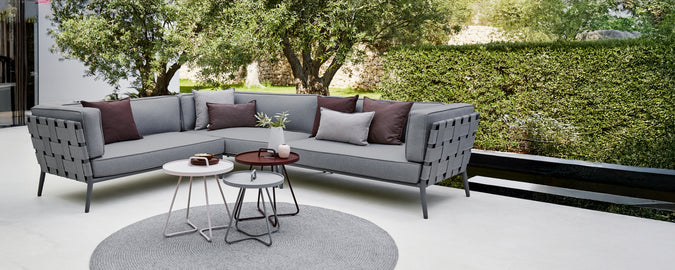 Modern grey sectional sofa with purple cushions and a round coffee table in a lounge area.