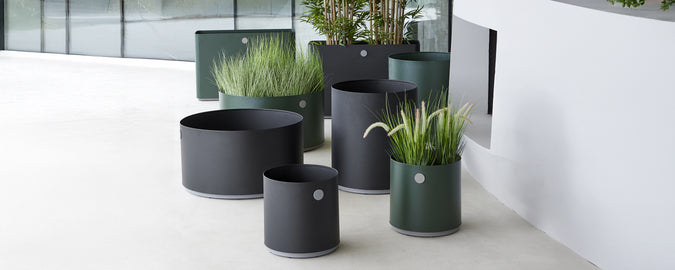 Modern black and green planters with greenery arranged in a contemporary setting.