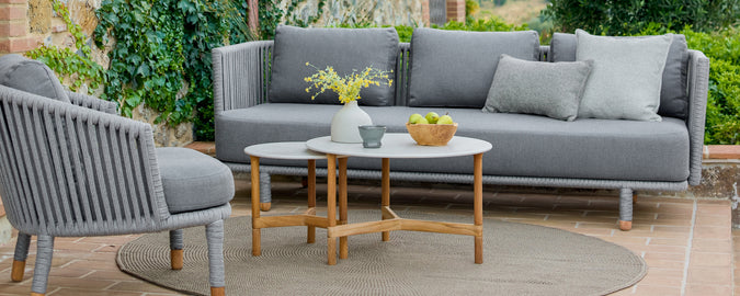 Modern outdoor lounge area featuring a grey sofa, grey chair, and wooden coffee table.