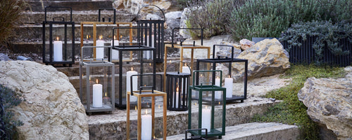 Modern outdoor lanterns in black, gold, and green arranged on stone steps.