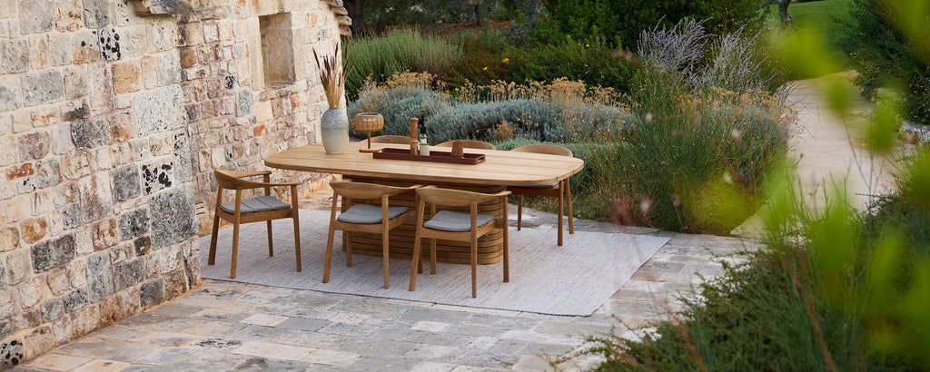 Rustic wooden table with matching chairs in a garden setting.