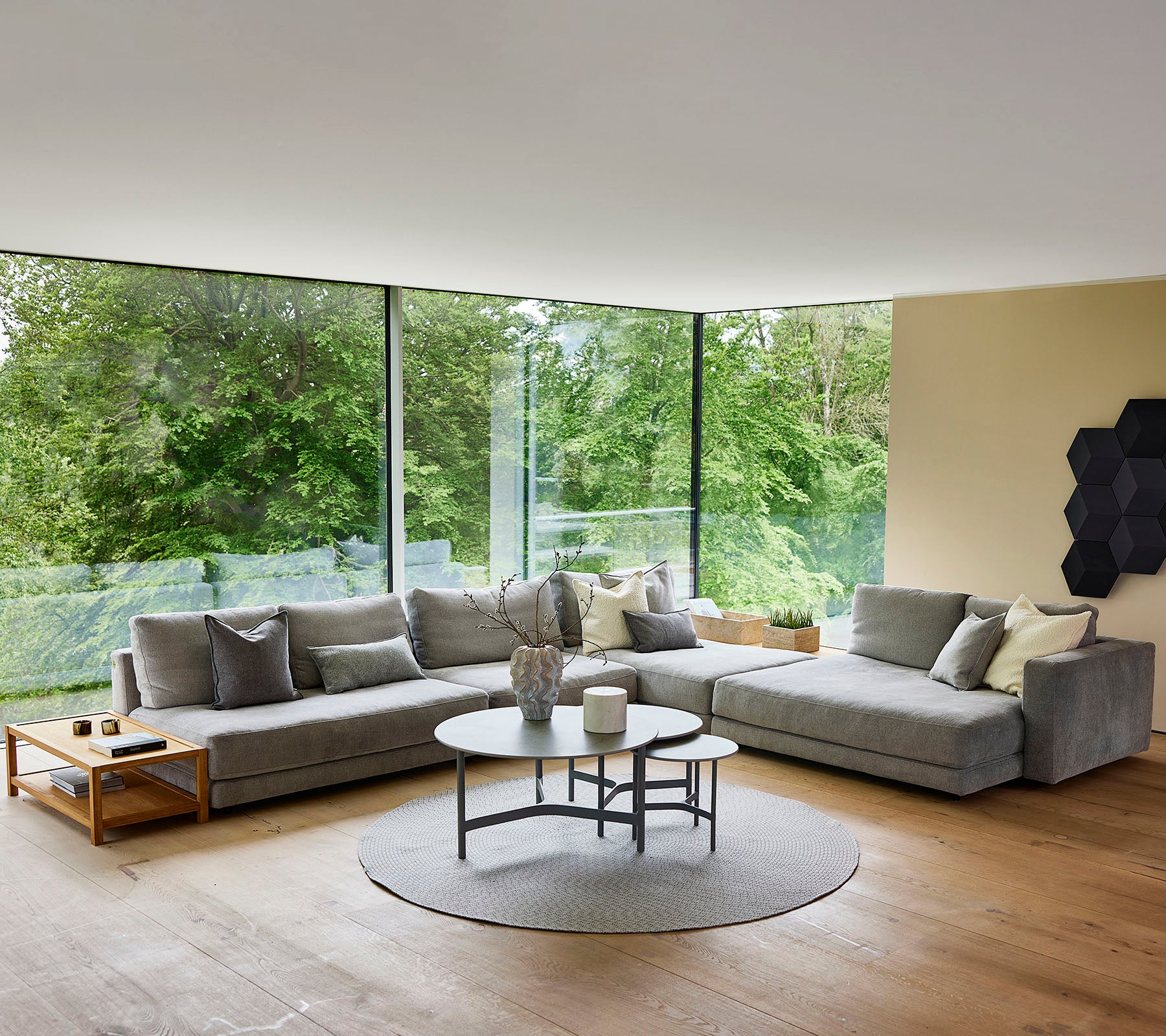 Open living room with gray sectional sofa and circular rug by large windows