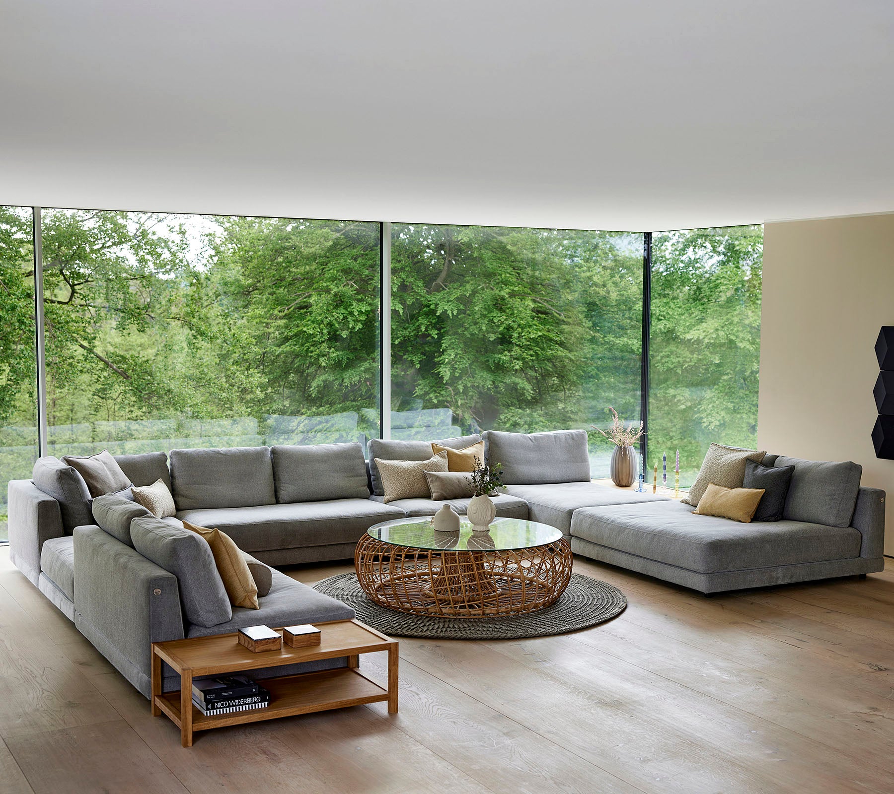 Spacious living room with gray sectional sofa, wicker coffee table, and large windows