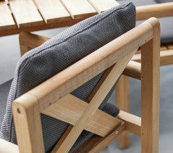 Wooden chair with a gray patterned cushion, featuring a crisscross design on the backrest and surrounded by wooden slats.