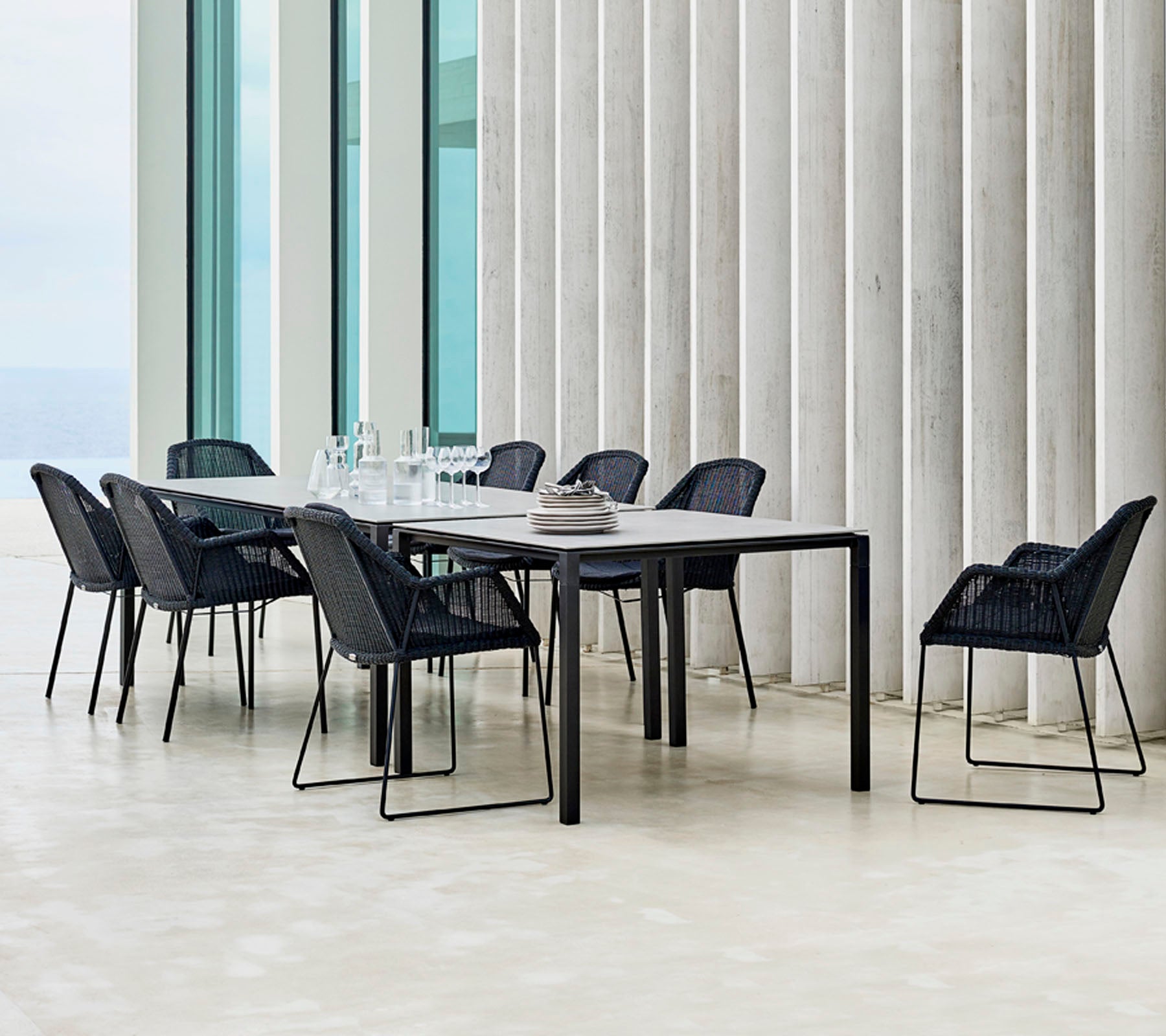 A modern dining table set with black chairs arranged around it, featuring minimalistic design elements and a sleek table setting.