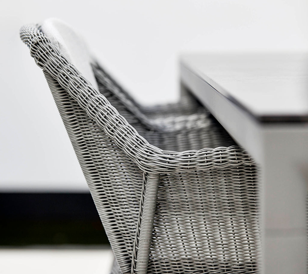 A close-up of a stylish gray wicker chair beside a sleek table, showcasing modern design and textures.