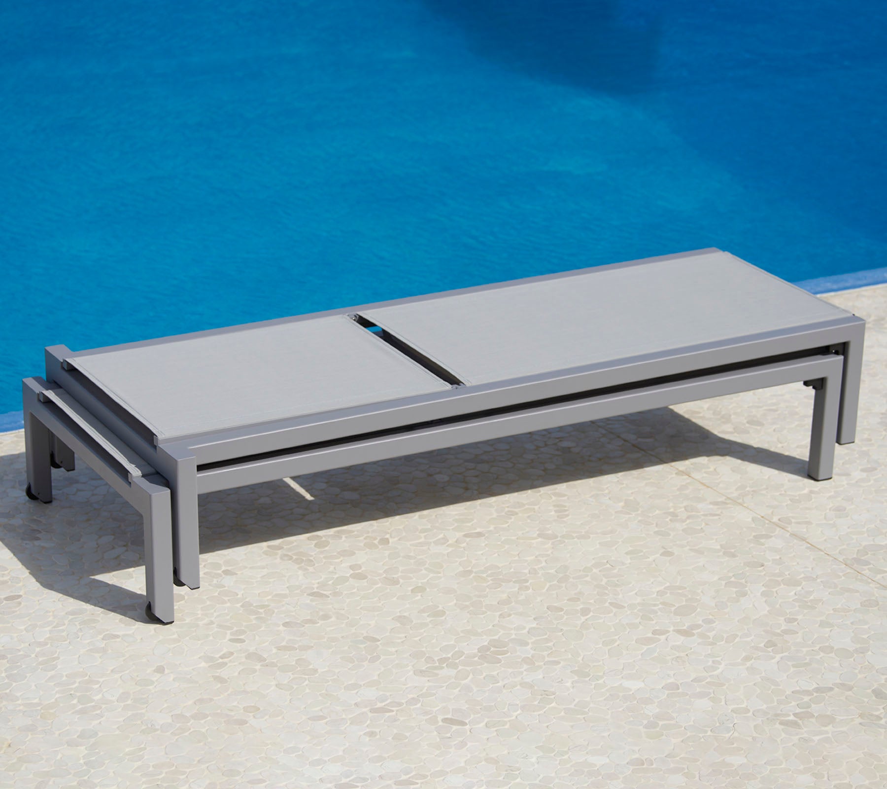 Stylish gray lounge bed beside a pool, featuring a sleek design and practical functionality for relaxation.