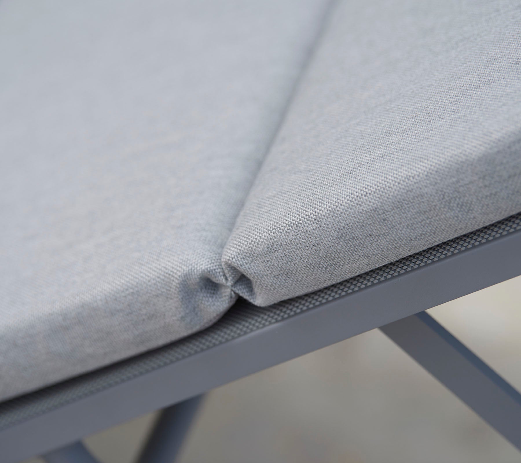 Gray cushioned seating fabric with neat stitching, showcasing a seamless design and durable support structure.