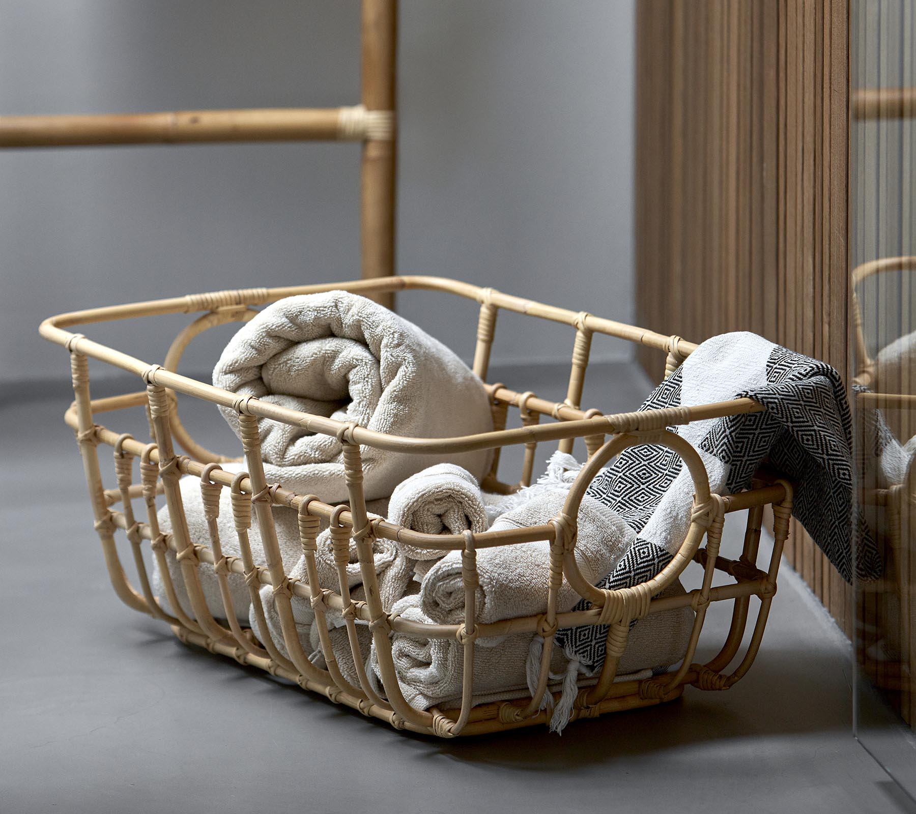 A woven basket filled with neatly rolled towels in soft, neutral tones, complementing a serene, minimalist setting.