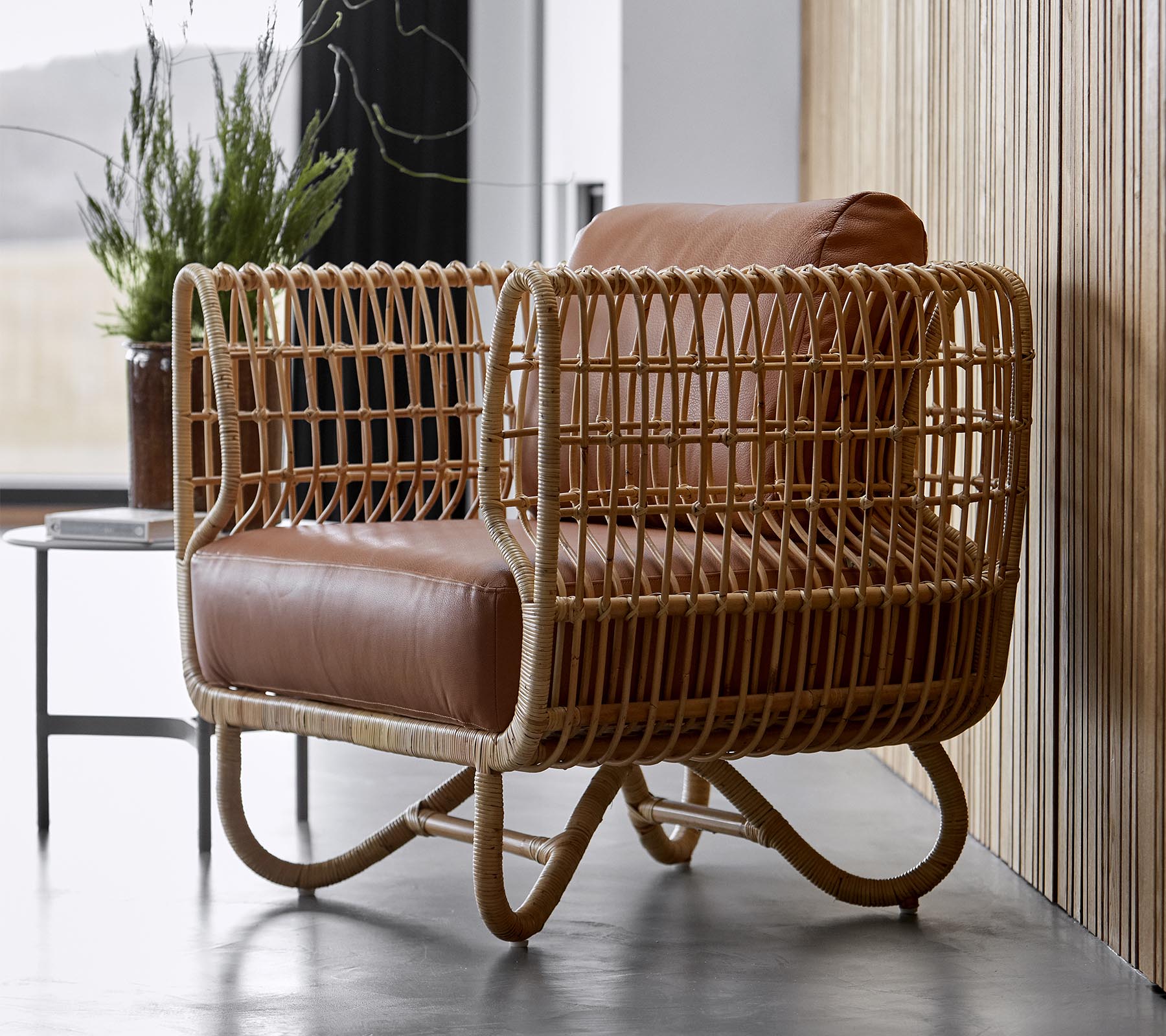 Stylish armchair featuring a woven rattan frame and plush brown leather cushions, perfect for modern decor.