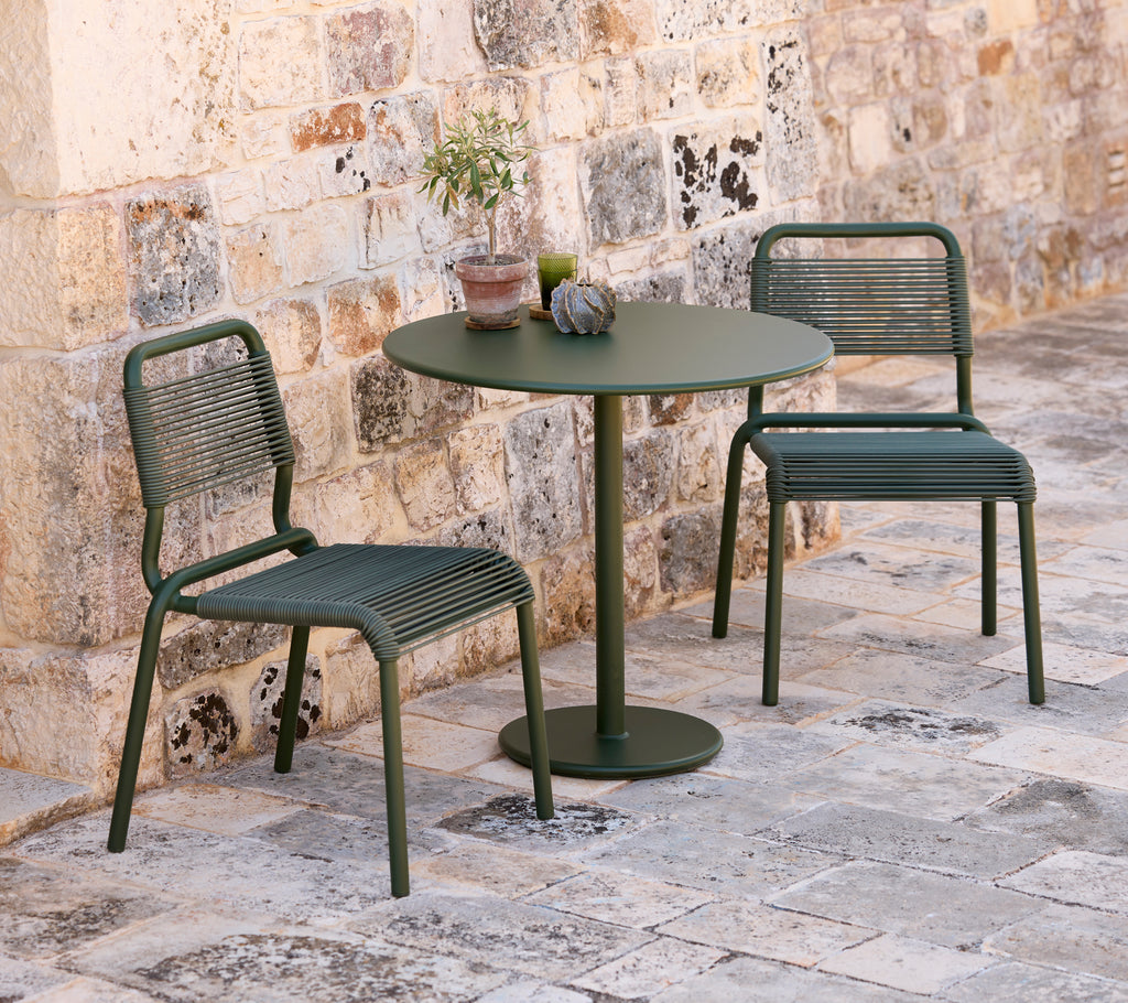 Two green chairs and a round green table in an outdoor setting.