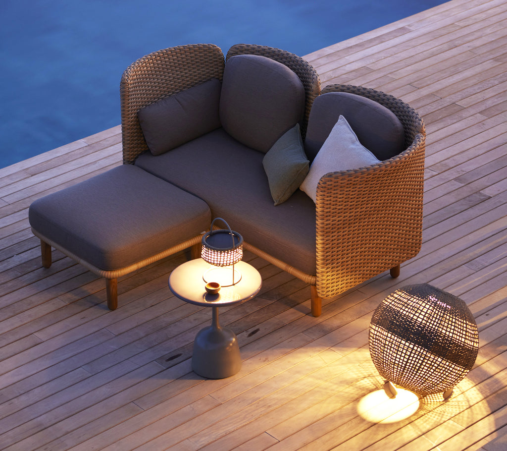 Cozy arch 2-seater sofa featuring a low backrest, accompanied by a small side table and decorative lantern. Perfect for relaxation.