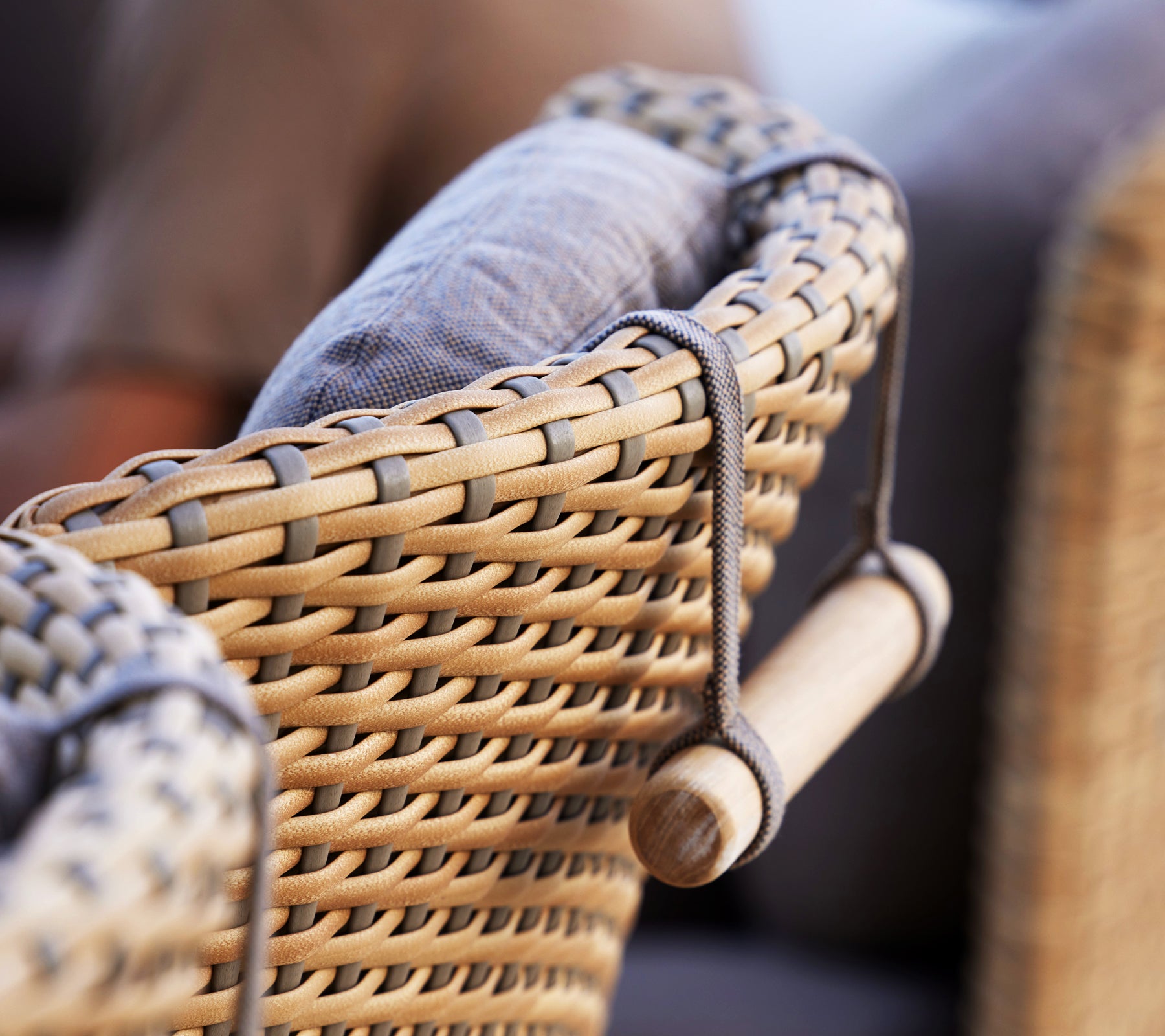Close-up of a woven chair armrest featuring a cushioned backrest and arching neck support for enhanced comfort.