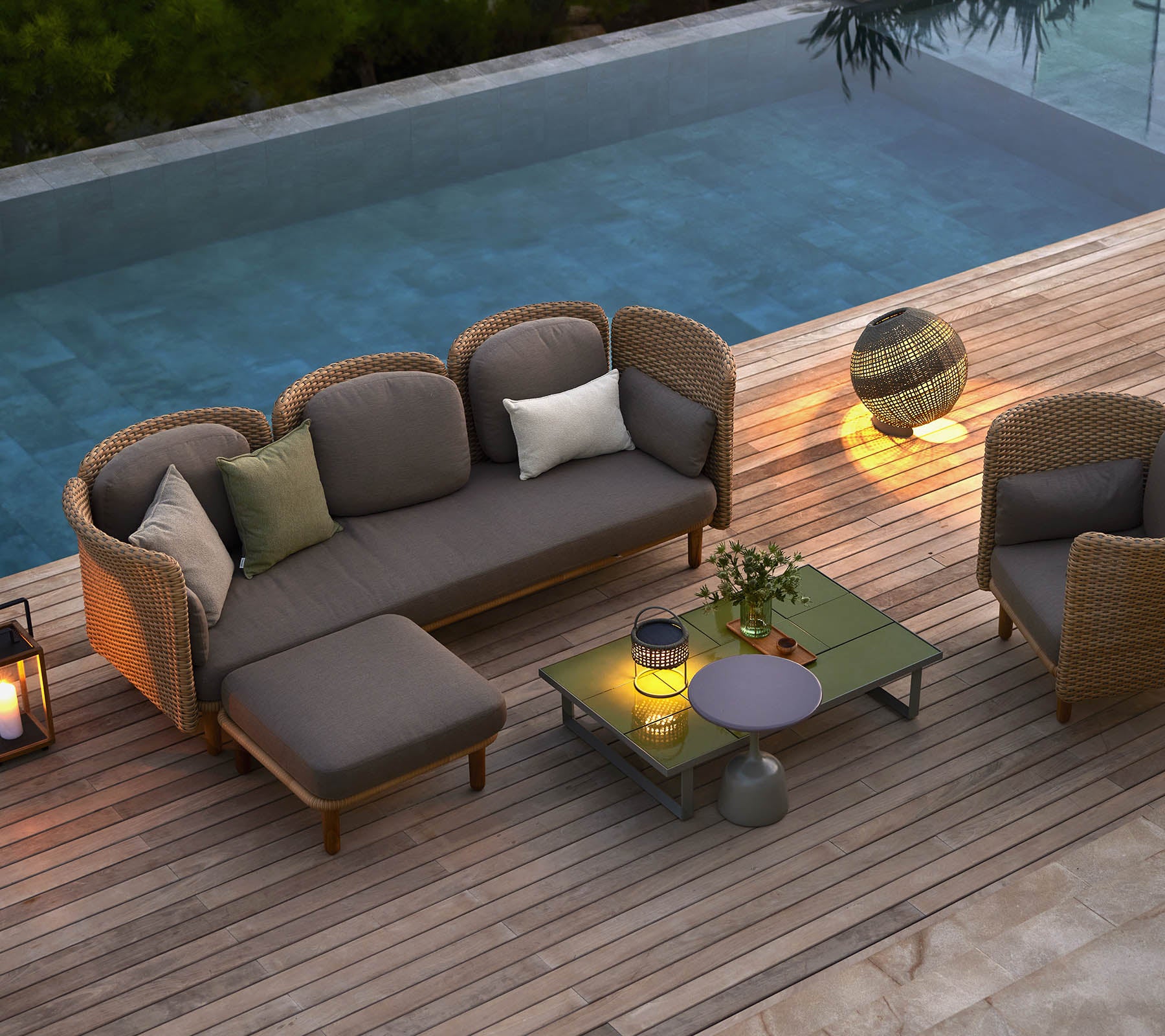 Stylish lounge seating with cushions, a coffee table, and ambient lighting, set beside a serene pool.