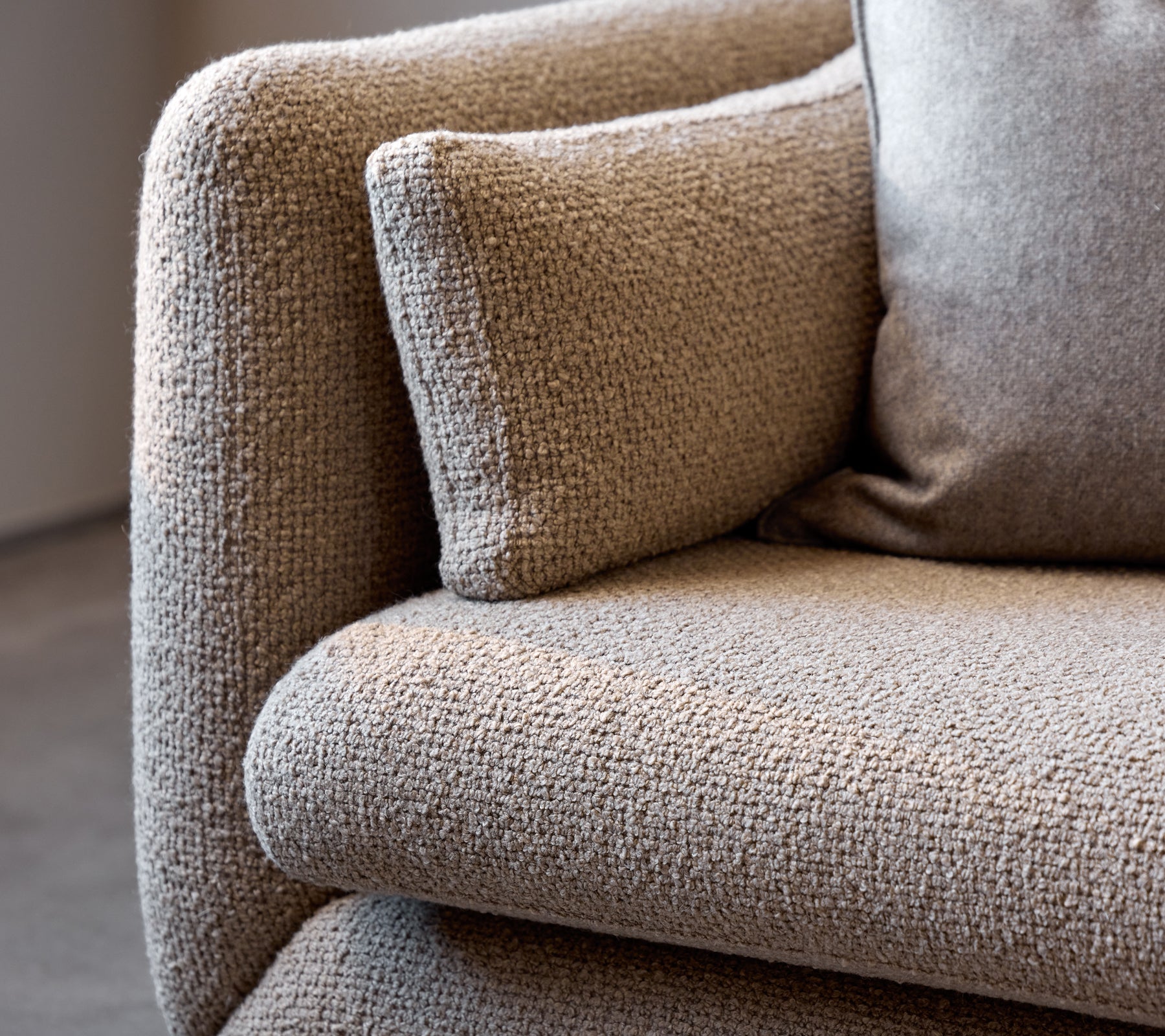 Close-up of a taupe Bloom sofa armrest, showcasing its textured fabric and plush cushion for added comfort.