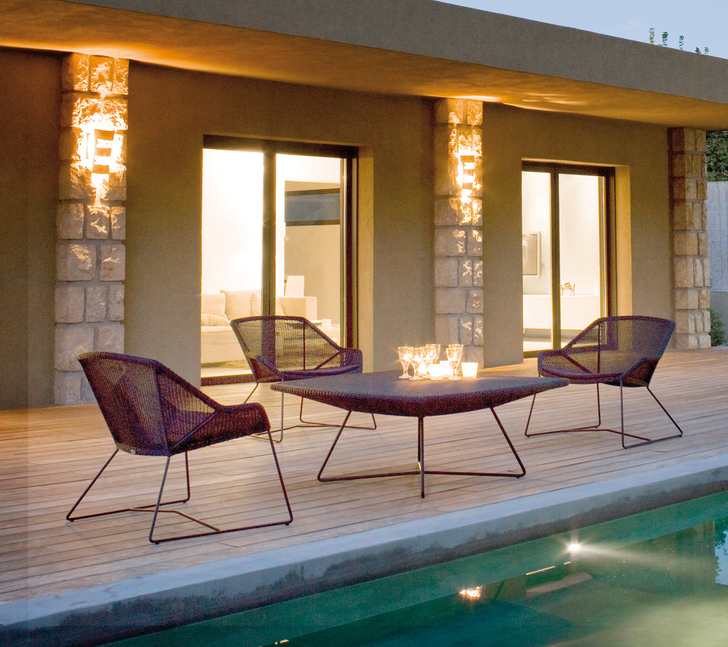 Modern outdoor setting with purple lounge chairs and a matching table near a pool.
