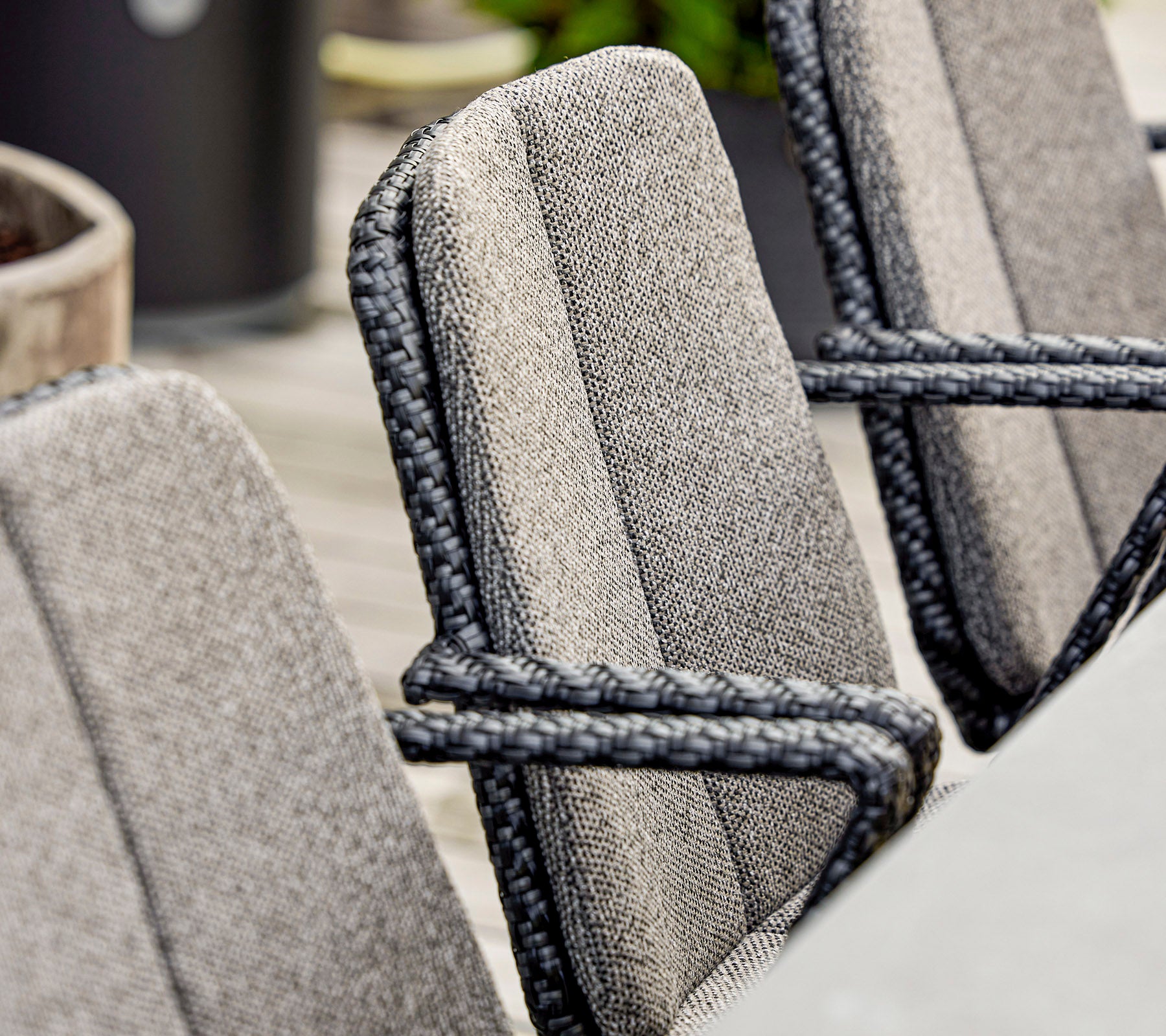 Close-up of stylish chairs featuring textured fabric and elegant rope detailing, suitable for modern outdoor seating.