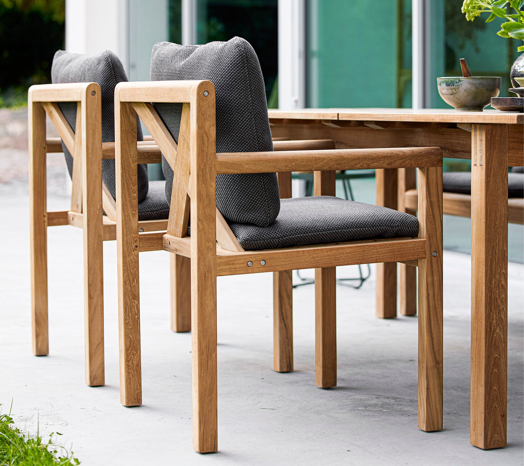 Wooden chairs with gray cushioned seats, designed for comfort, complementing a wooden table in a stylish setting.
