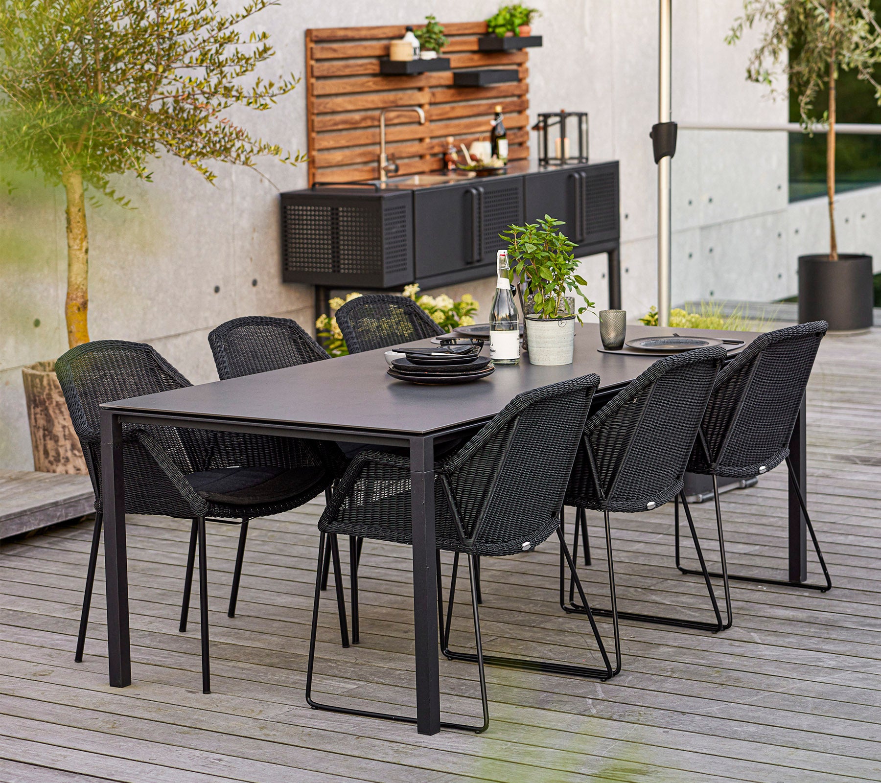 A modern dining set featuring a rectangular table and six stylish chairs, complemented by decorative plants and dishware.