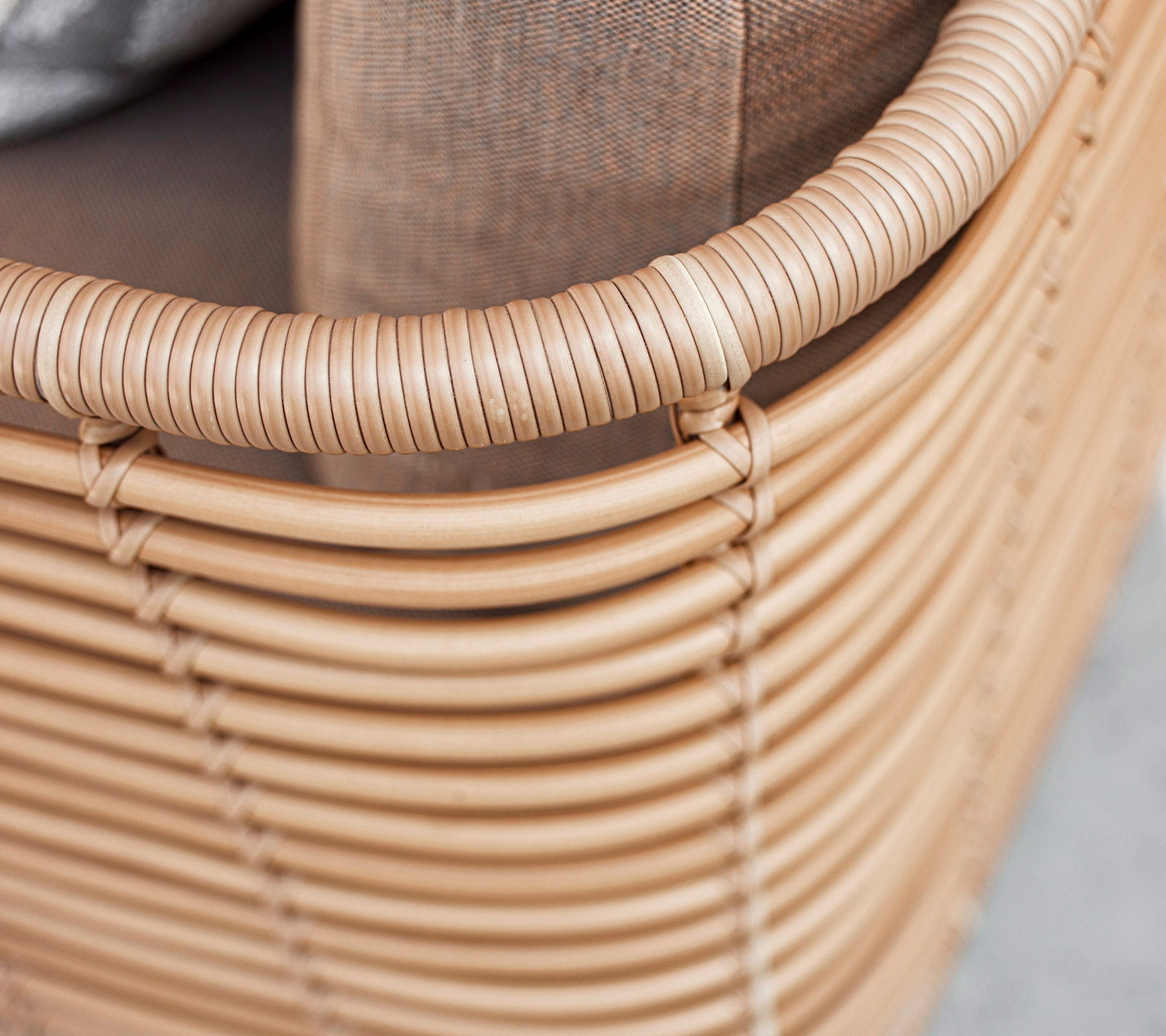 Light-colored woven seating with a rounded edge and a textured cushion, showcasing a modern, minimalist design.