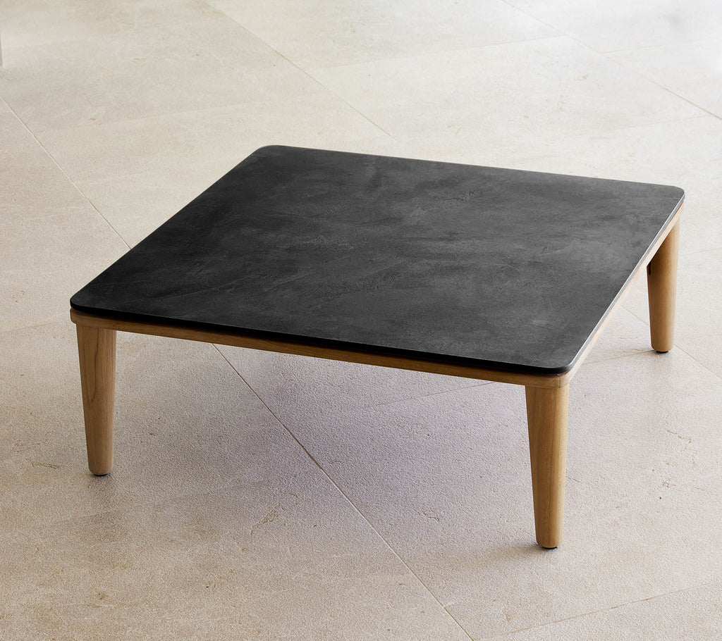Square black table with wooden legs in a minimalist setting.