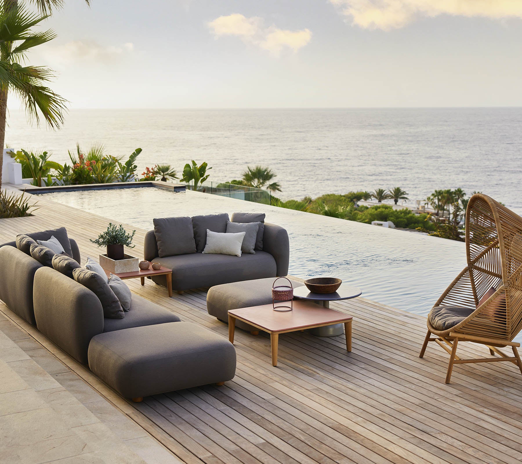 Stylish lounge area featuring a cozy hive hanging chair and modern seating, complemented by scenic views of the ocean and lush greenery.