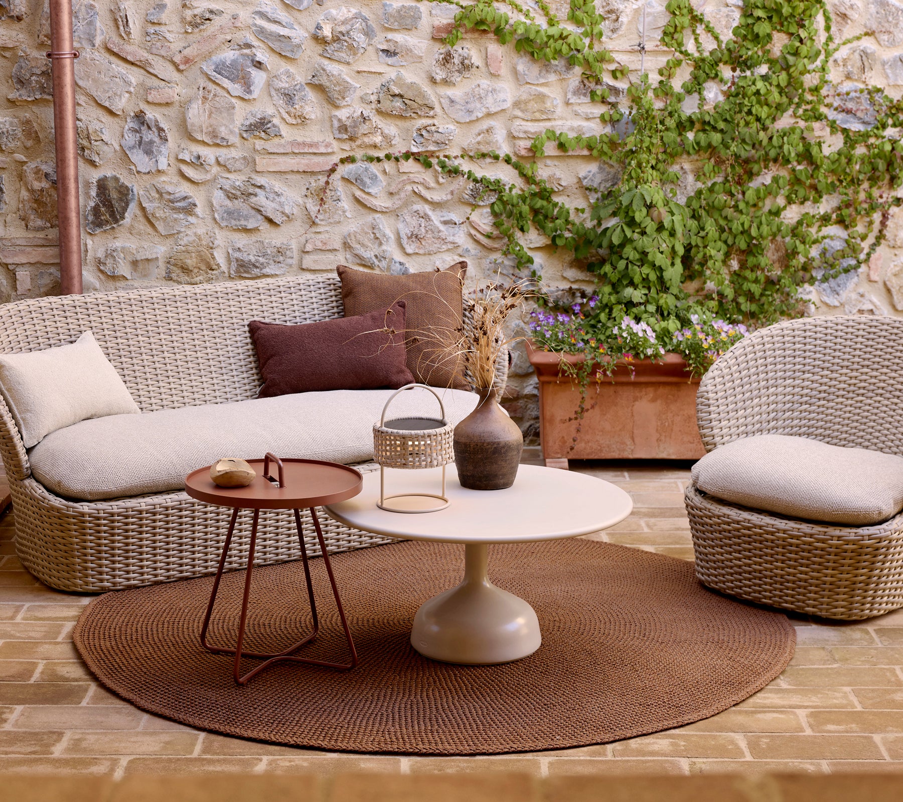 Cozy seating area featuring a knit rug, a glossy coffee table, and a stylish side table, accented by decorative cushions and greenery.