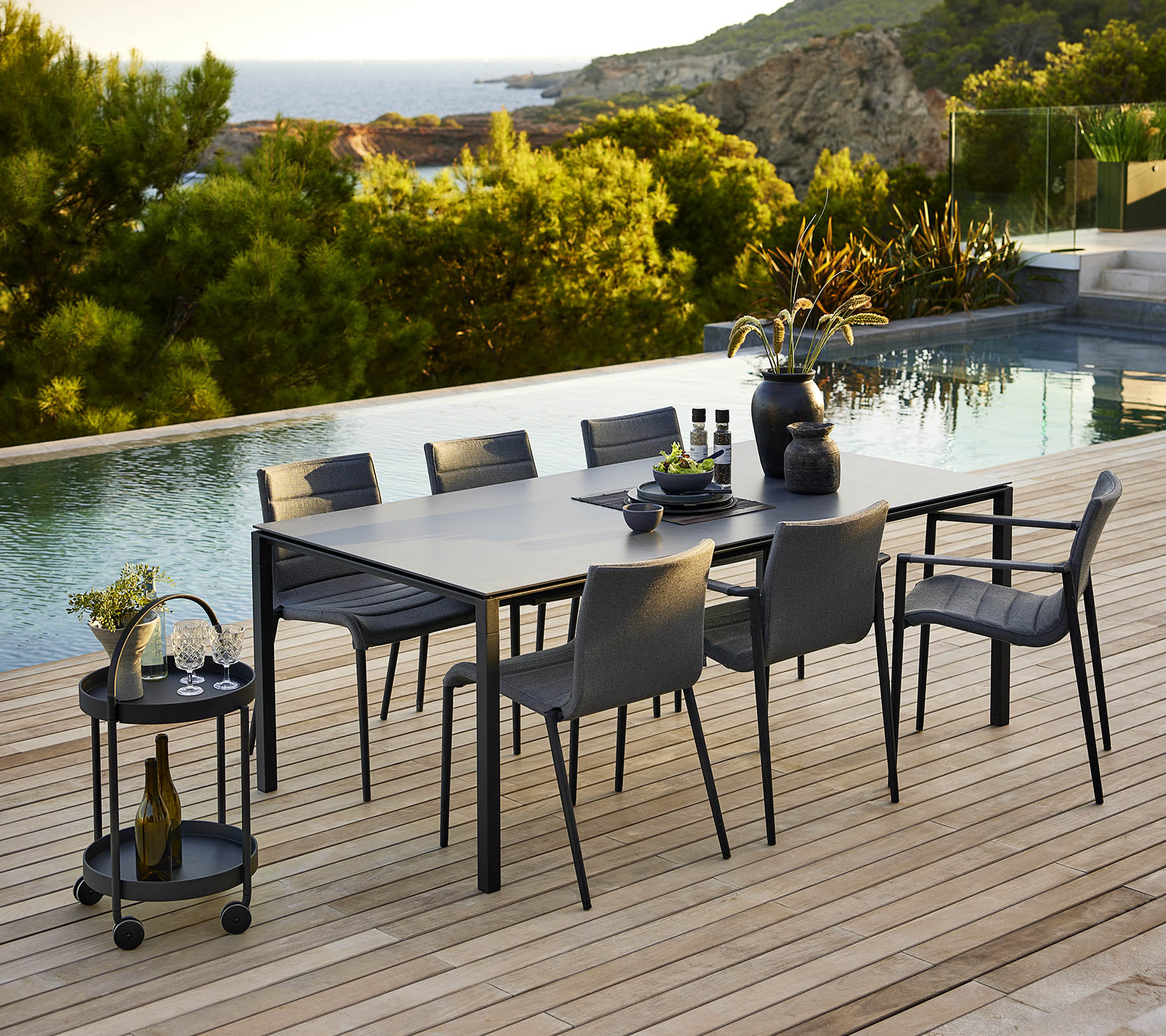 Stylish dining setup featuring a sleek table and matching chairs, complemented by decorative accessories and a serene outdoor backdrop.