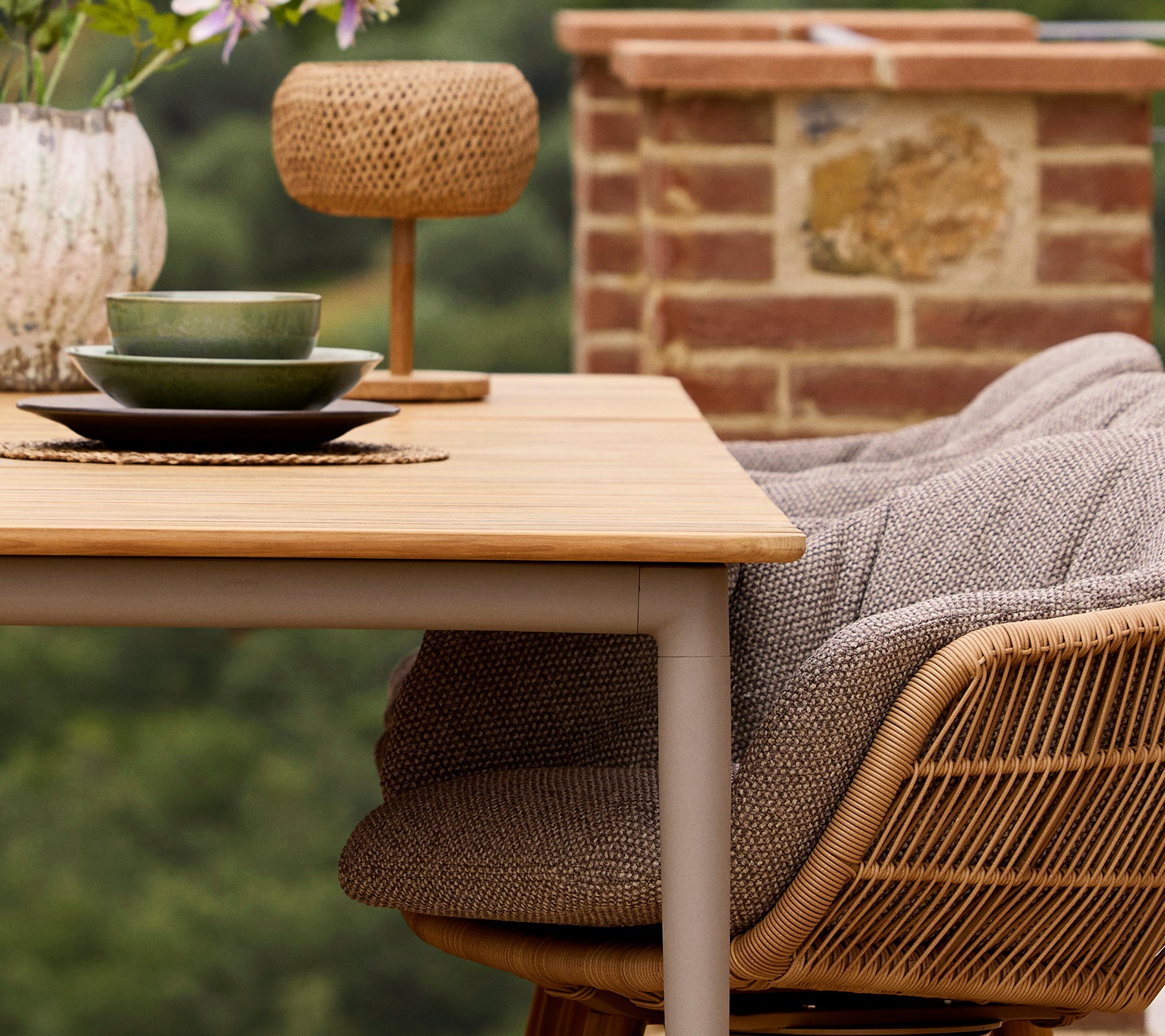 A Core dining table with green plates and a decorative vase, accompanied by a Stay chair featuring a cozy cushion and an Illusion Glow lamp.