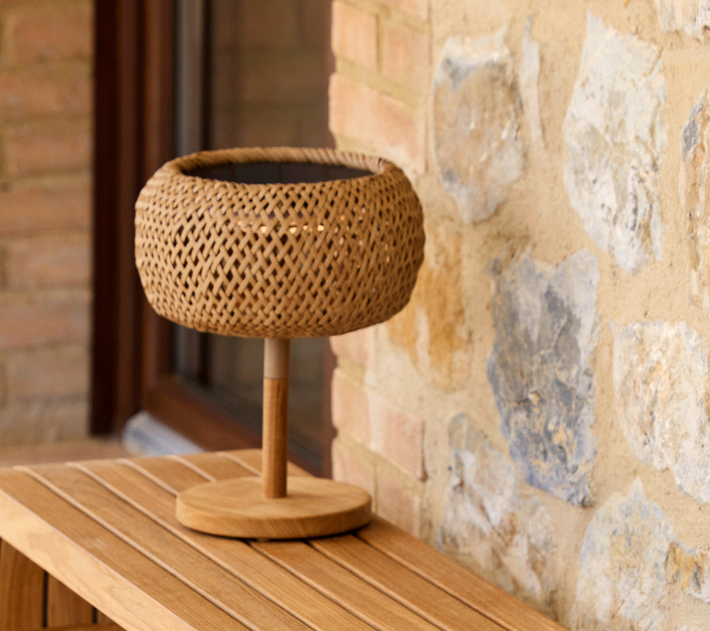 Woven lantern-style table lamp with a wooden base, adding a warm glow to a rustic setting. Perfect for cozy lighting.