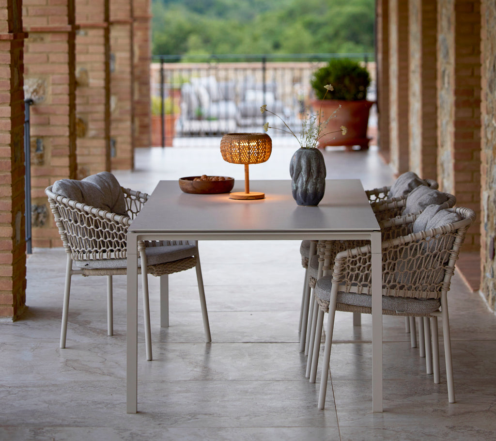 A small, glowing table lamp on a sleek table, surrounded by stylish ocean chairs, creating a cozy and inviting atmosphere.