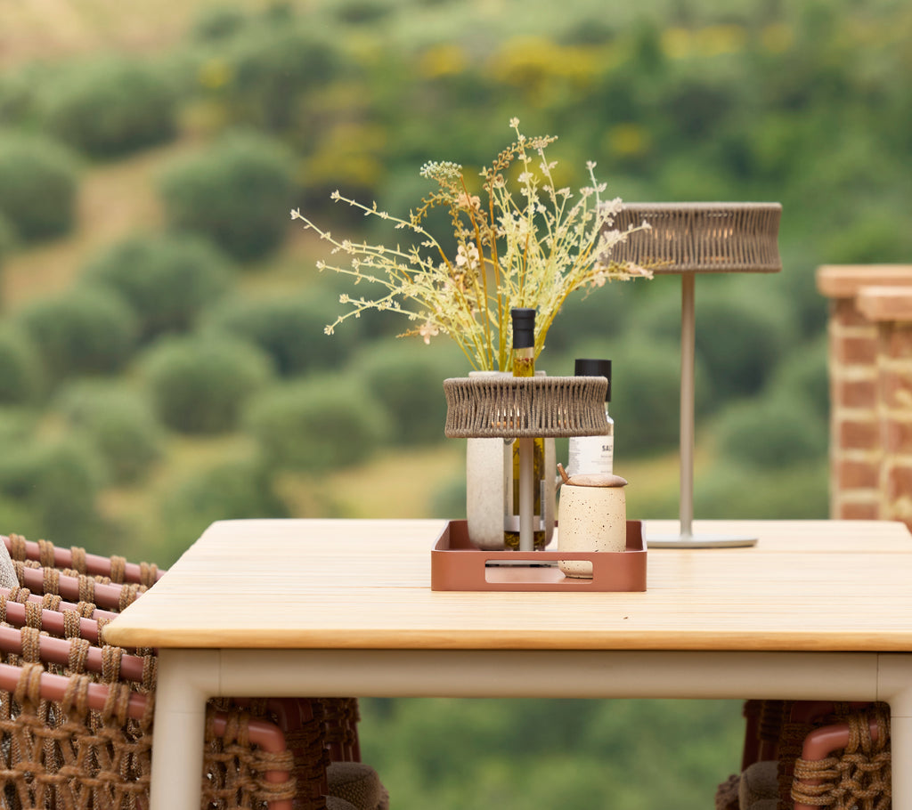 A stylish dining table featuring an illusion lamp and a vase of flowers, creating an elegant centerpiece in a serene setting.