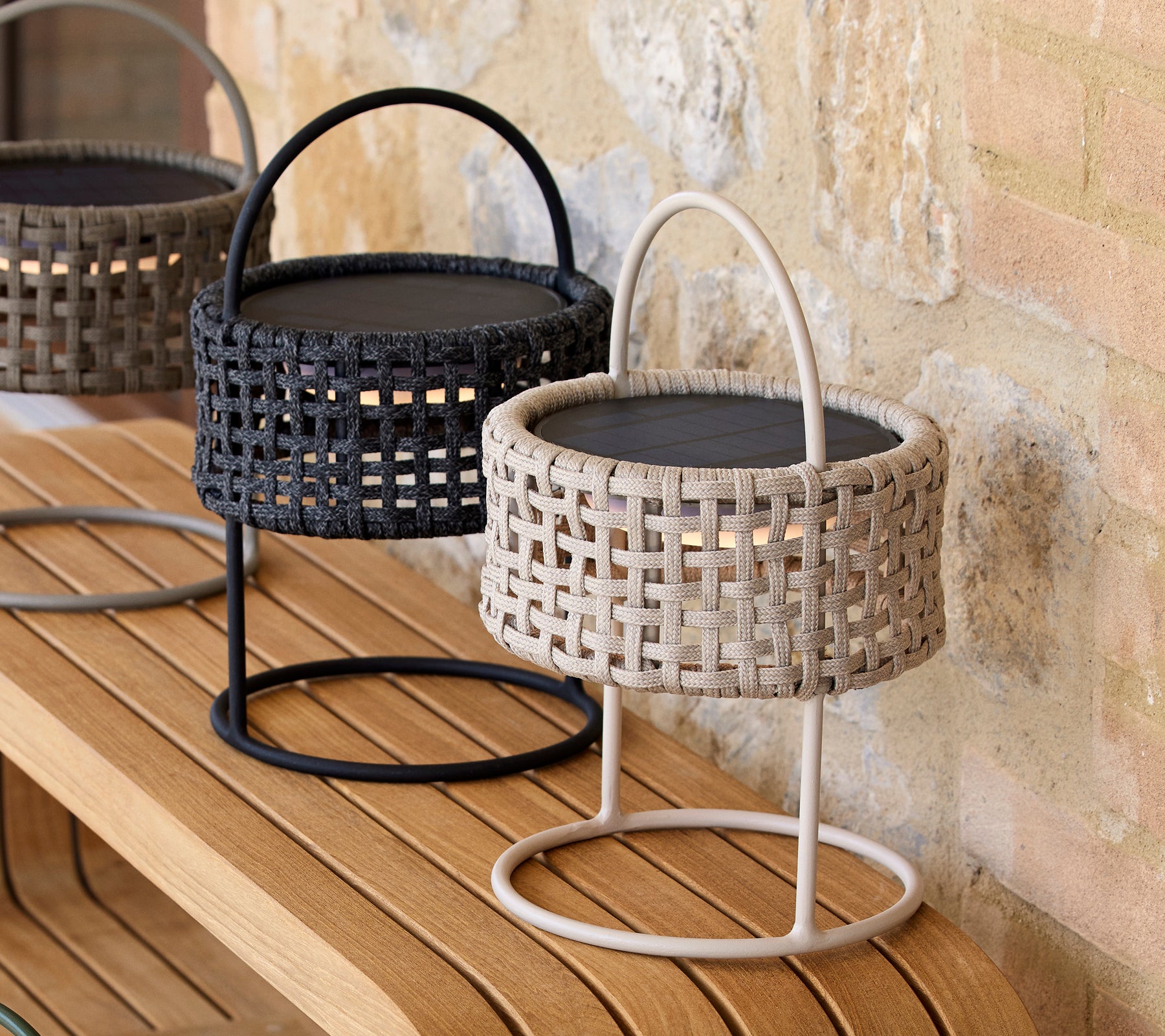 Two decorative illusion lamps in sand and black colors with woven designs, placed on a wooden surface.