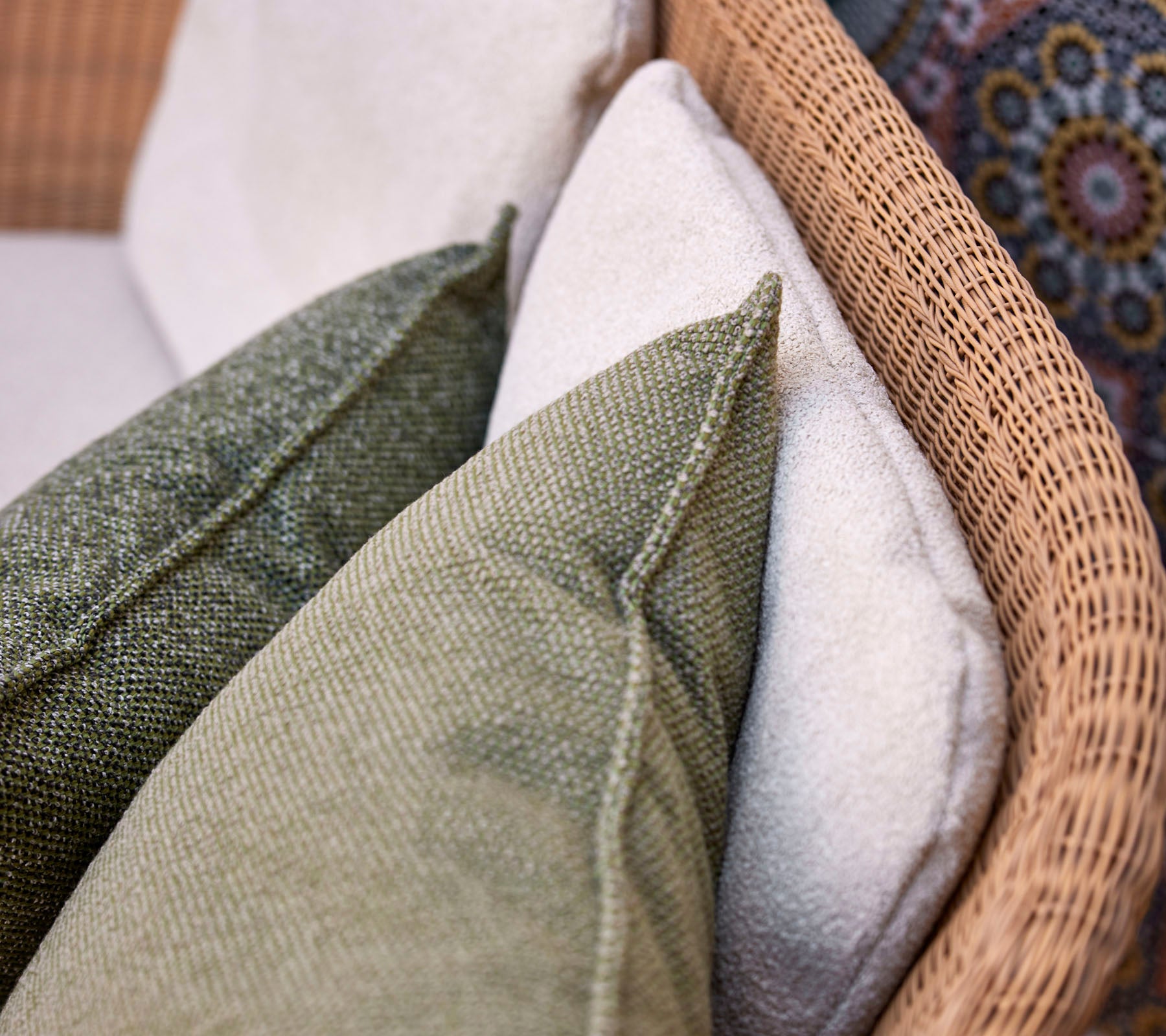 A close-up view of decorative cushions in various textures and colors, arranged on a woven seating surface.
