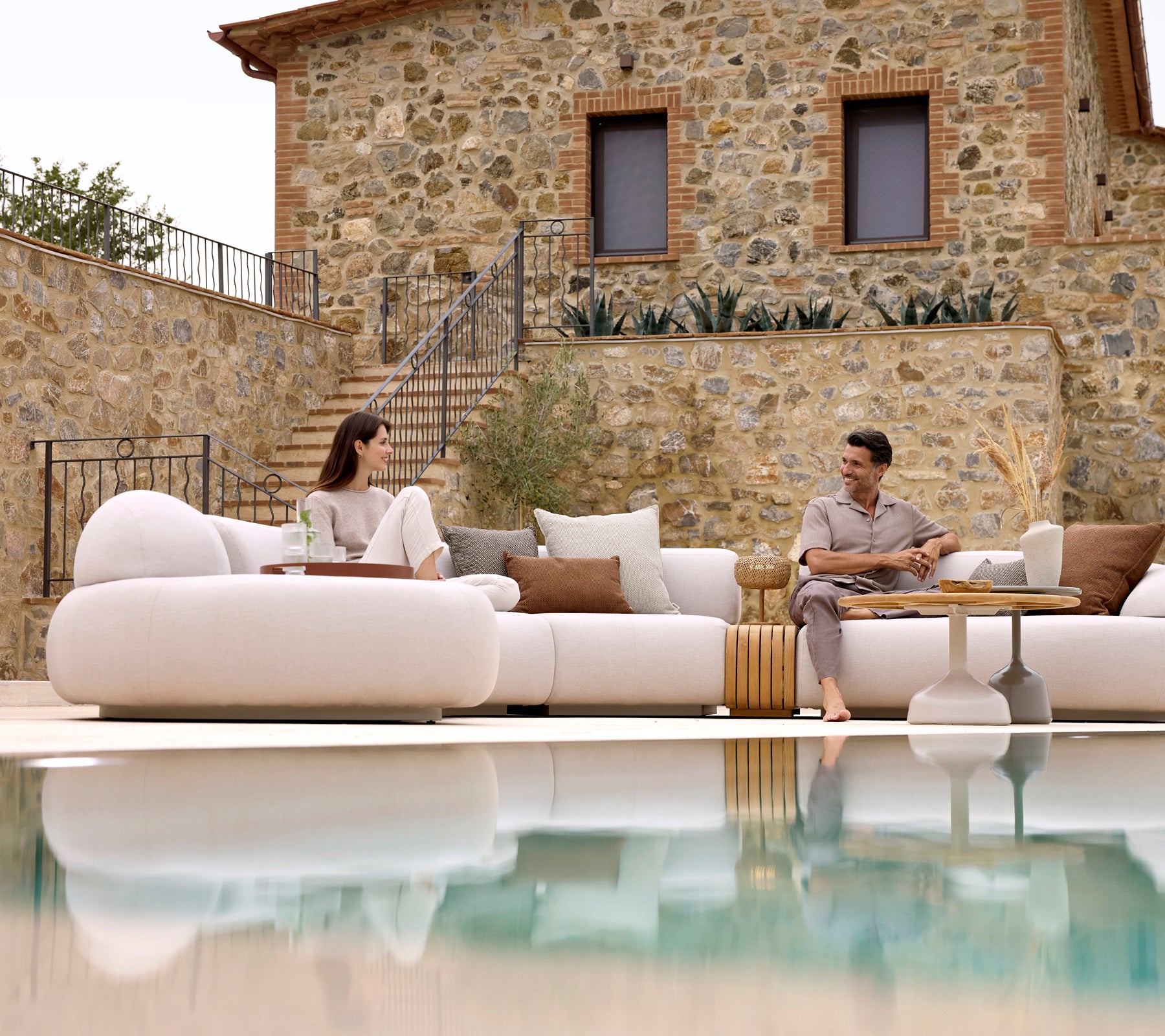 Two people relax on a mellow lounge sofa, paired with a Glaze coffee table and a mellow coffee table, reflecting a serene atmosphere.