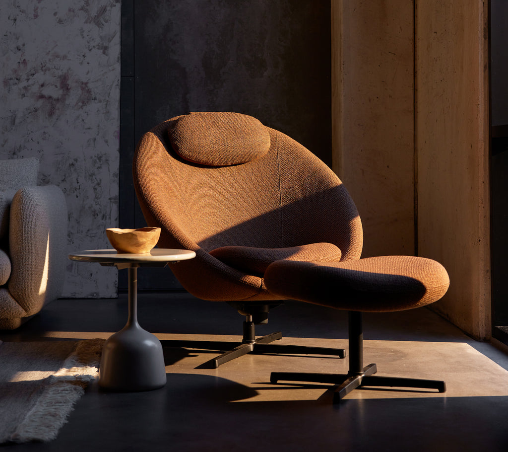 Umber brown Pace chair with a matching footstool, complemented by a small side table featuring a wooden bowl.