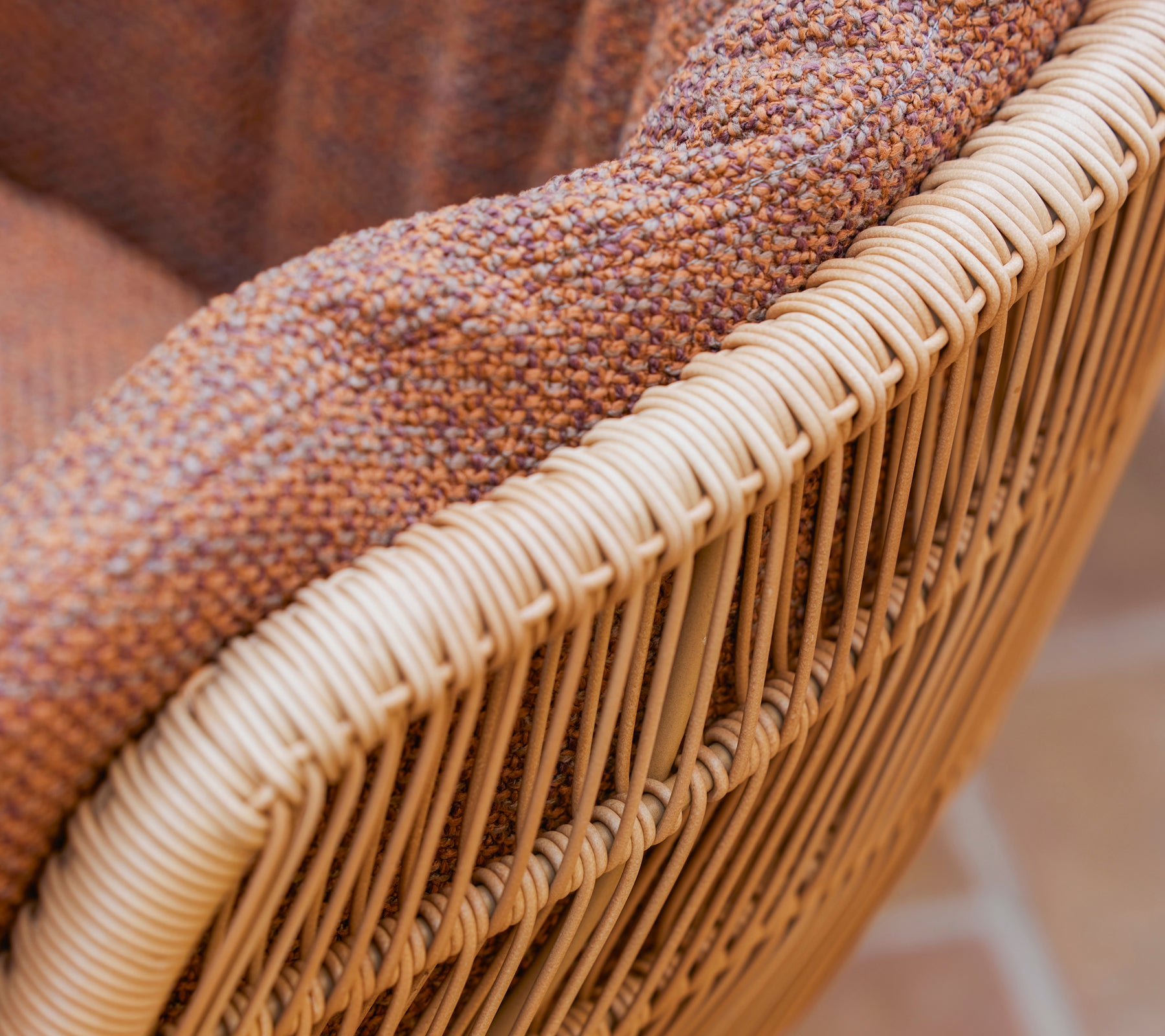 Close-up of a Stay dining chair featuring a textured brown Rise cushion and a woven natural fiber frame.
