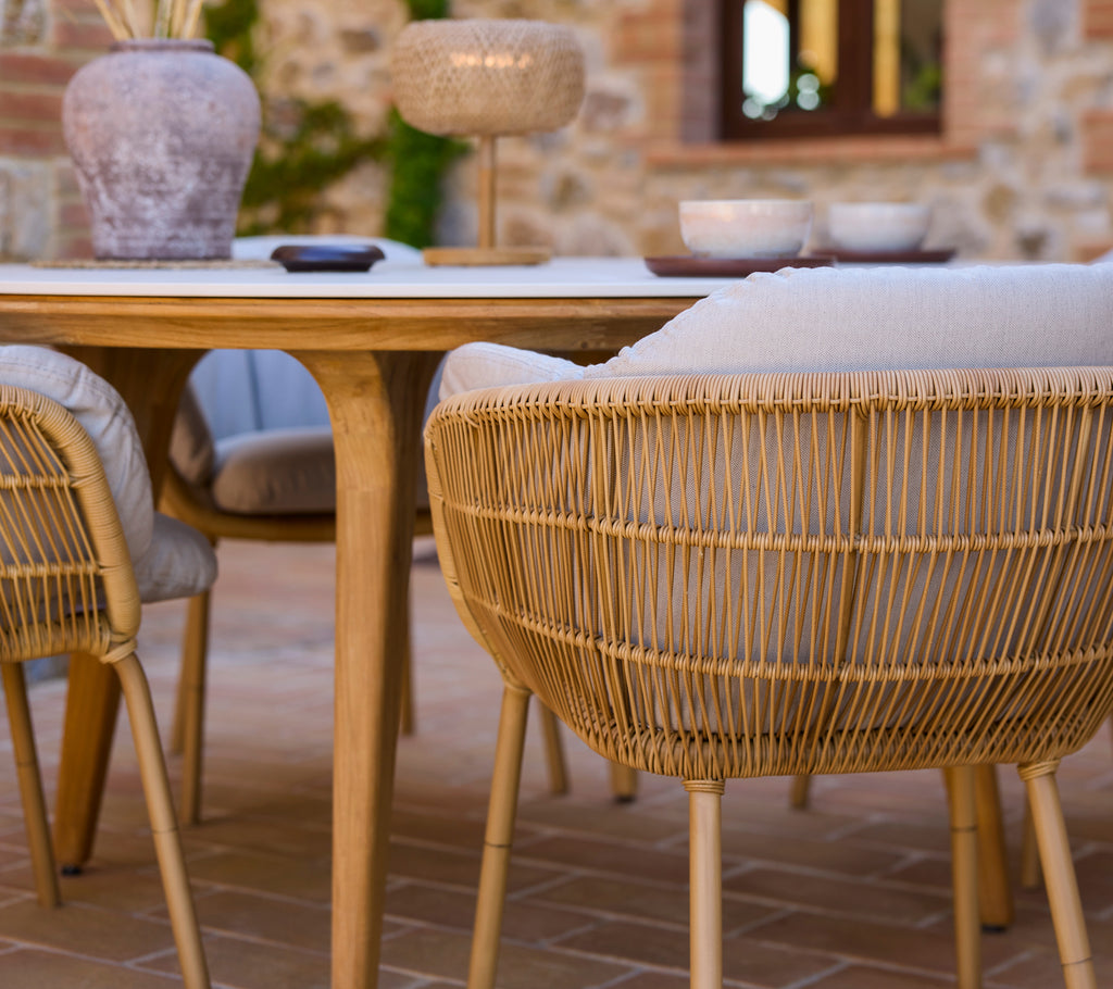 Stylish dining setting featuring woven chairs with aluminium legs surrounding a modern wooden table, complemented by decorative elements.