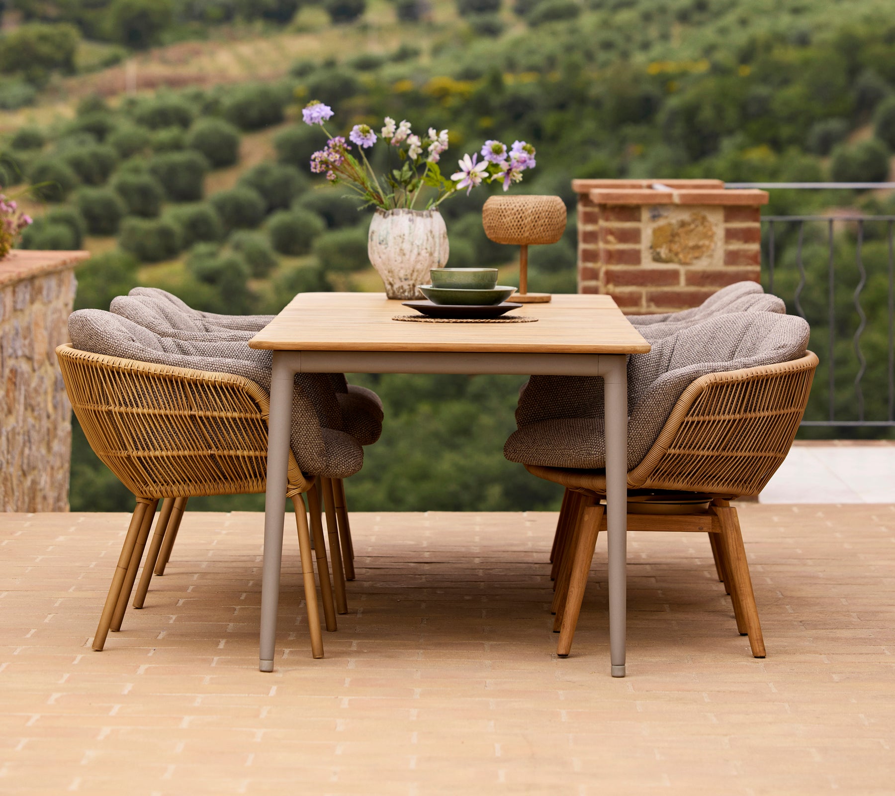 Stylish dining setup featuring a wooden table, two Stay chairs with aluminum legs, and a vase of flowers with decorative accessories.