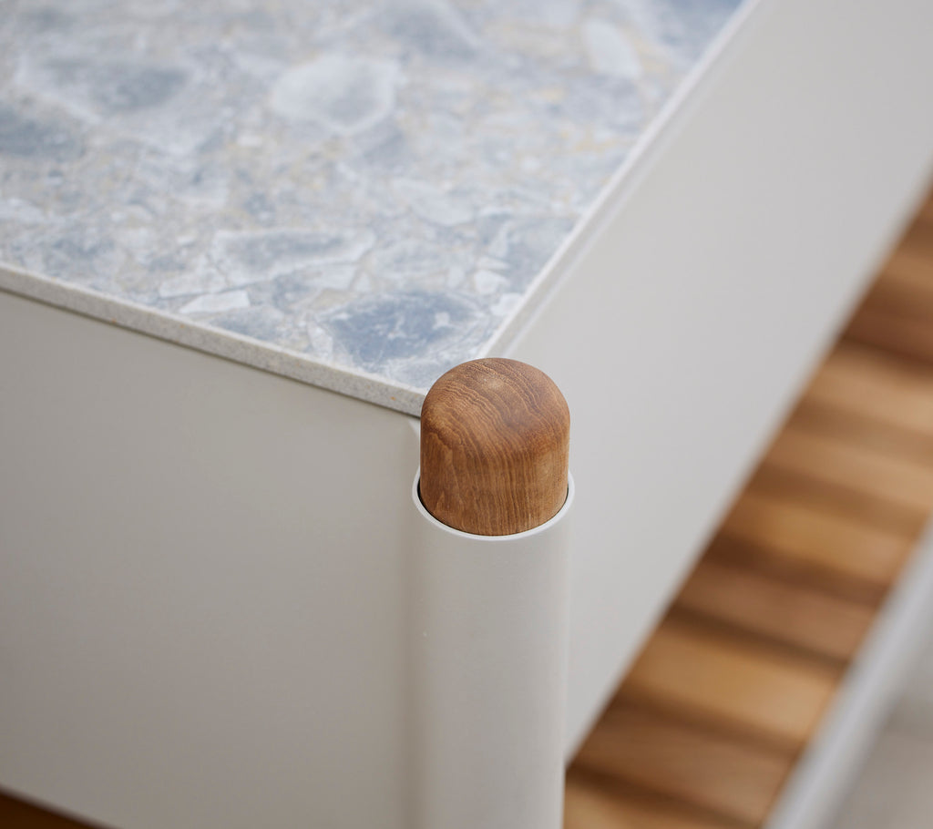 Wooden corner detail of a piece of furniture with a textured surface and vertical supports, emphasizing a modern aesthetic.