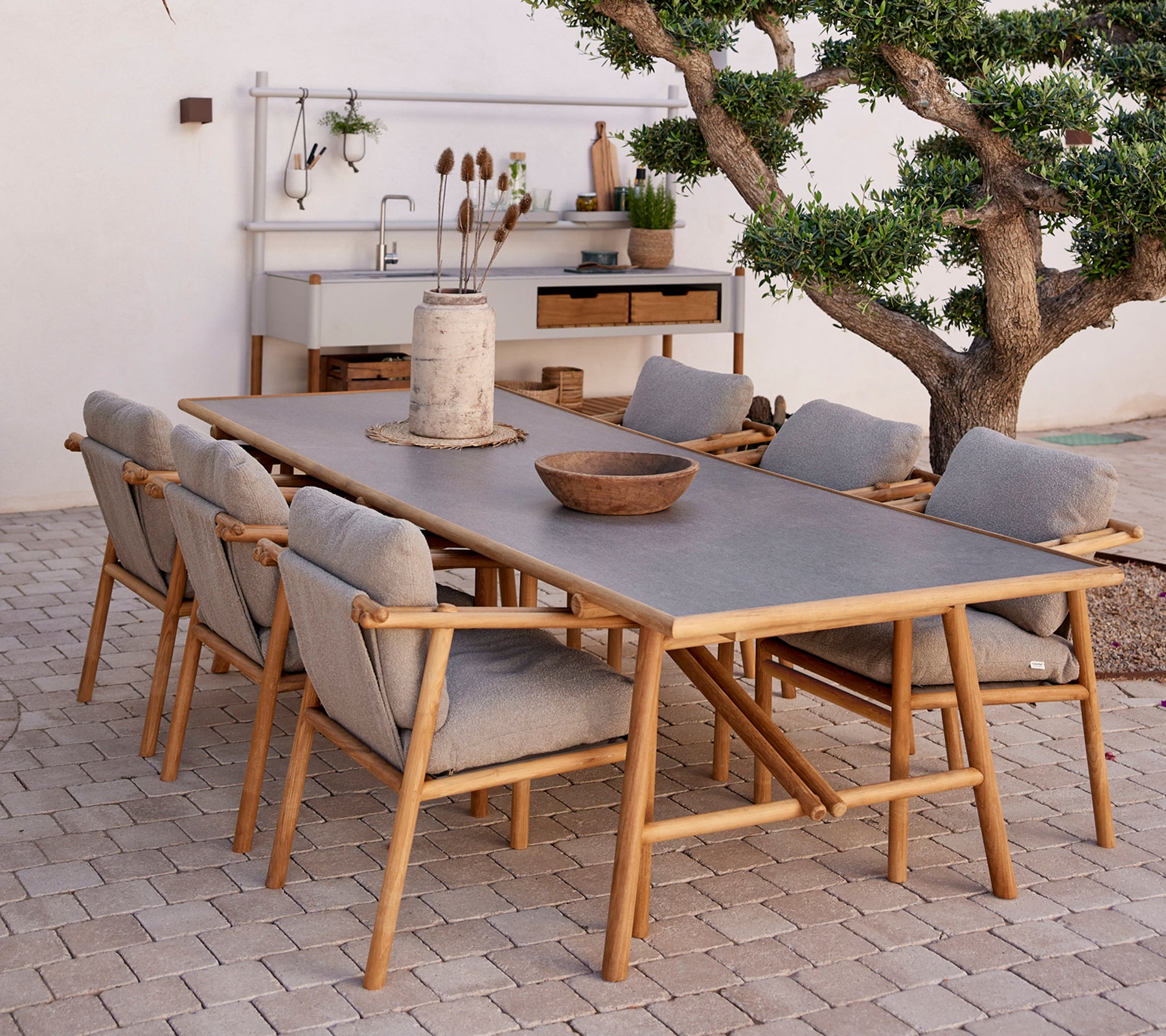 Teak dining table surrounded by comfortable chairs, featuring natural elements and a minimalistic decor style.