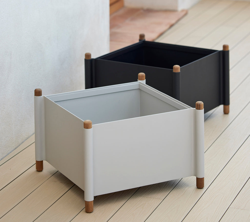 Two square planters in gray and black with wooden legs, designed for modern decor and suitable for various plants.