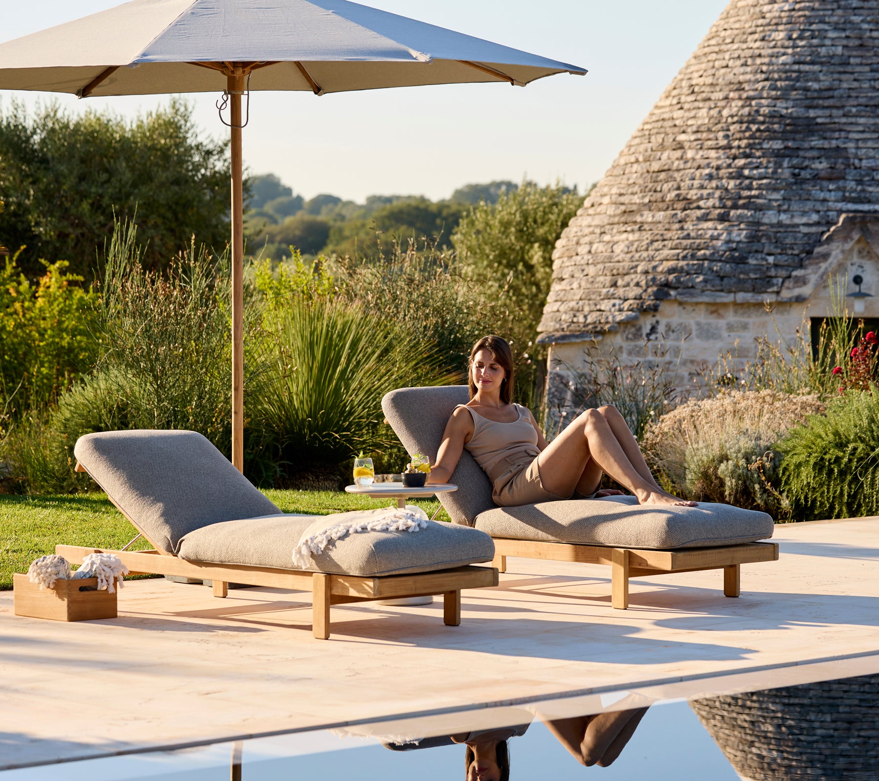 Two Vista sunbeds with thick cushions under umbrella on a patio