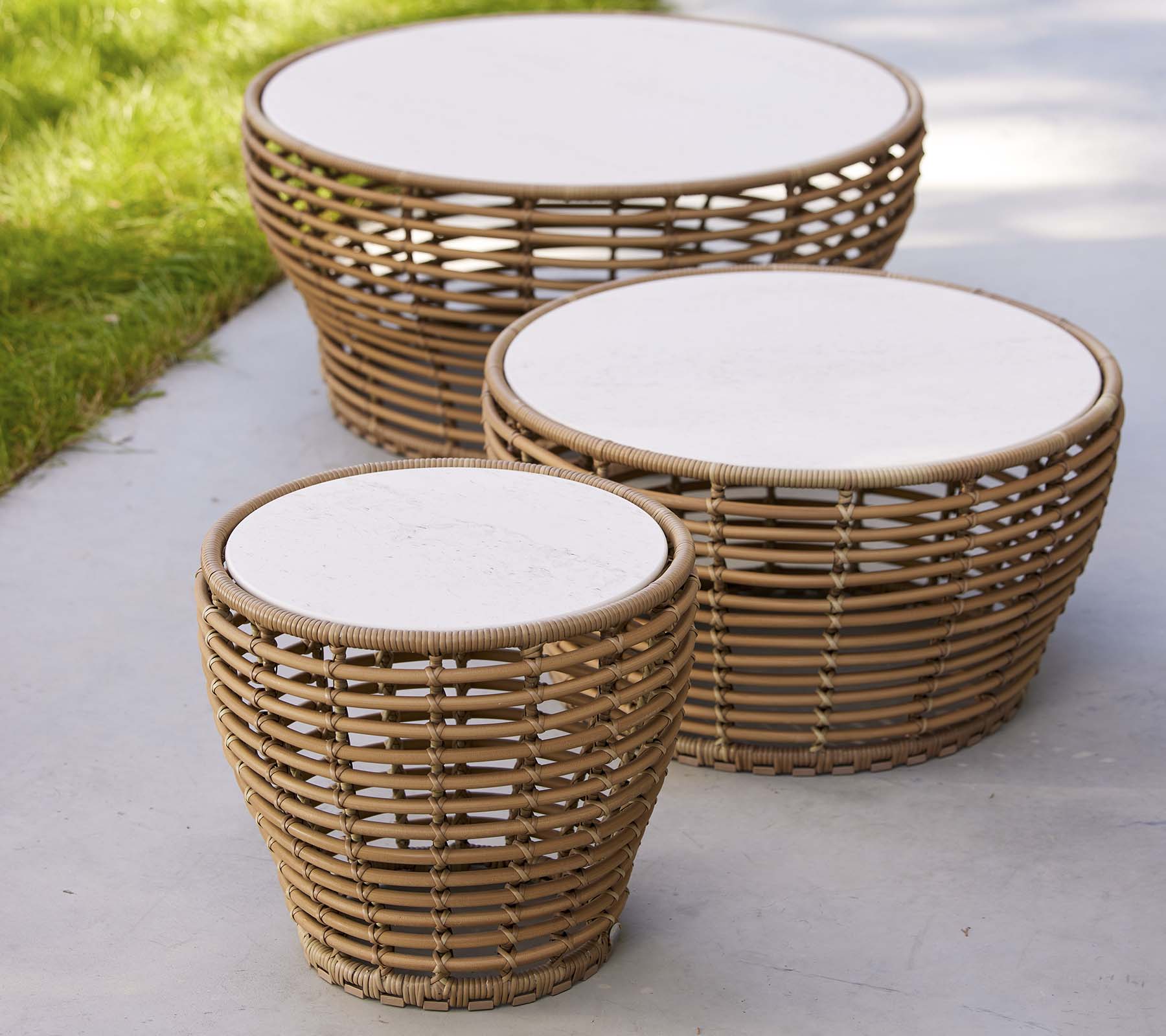 Three woven basket coffee tables in varying sizes, featuring round white tops and a natural design, ideal for a stylish living space.